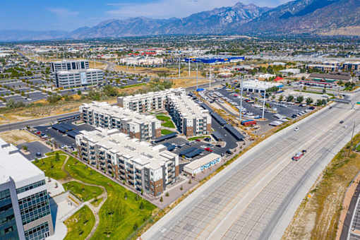 A large building complex is situated in the middle of a highway and a parking lot.