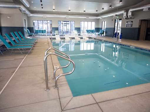 A large indoor swimming pool with blue water and metal handrails.