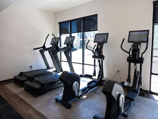 A gym with treadmills, elliptical machines, and a stationary bike.