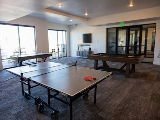 A ping pong table is in the middle of a room with a pool table.
