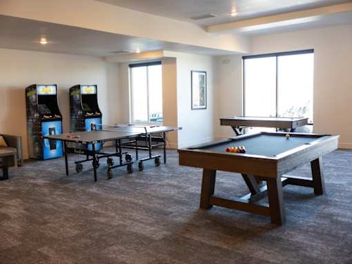 A room with a pool table and two arcade machines.