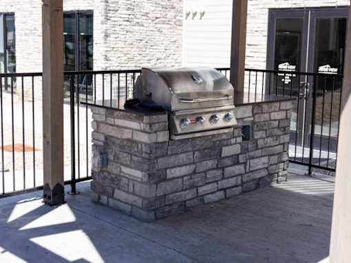 A silver grill is on top of a stone pillar.
