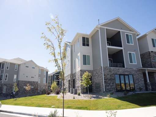 A modern two-story building with a stone facade and large windows.