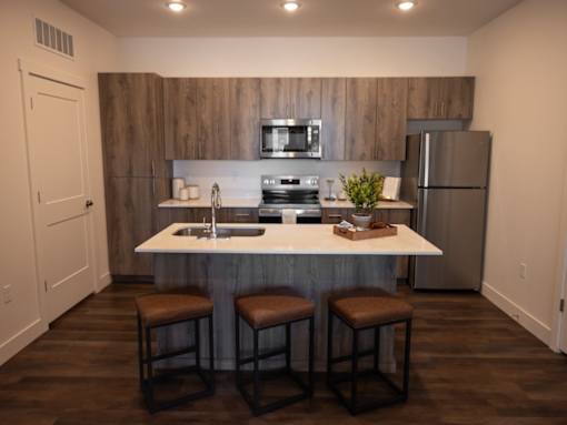 A kitchen with a white countertop and brown bar stools.