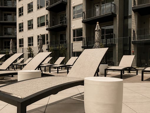 A row of sun loungers are in front of a building.