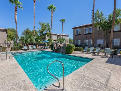 A swimming pool surrounded by palm trees and lounge chairs.