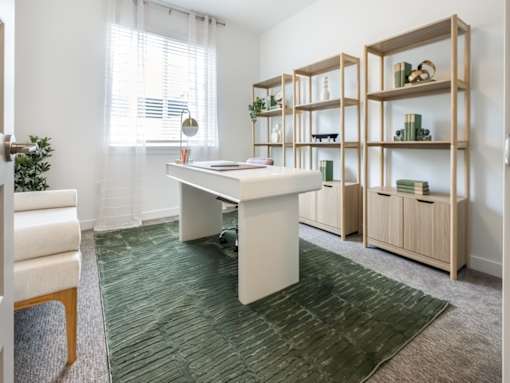 A room with a desk, chairs, and shelves.