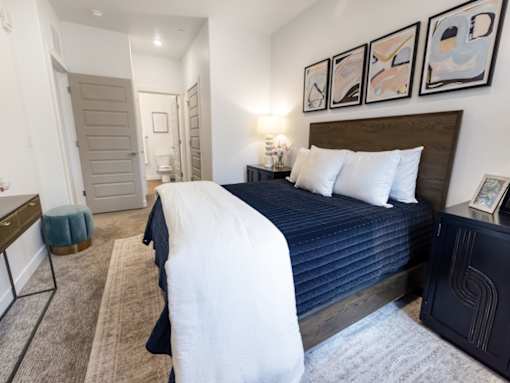 A bedroom with a large bed and a painting on the wall.