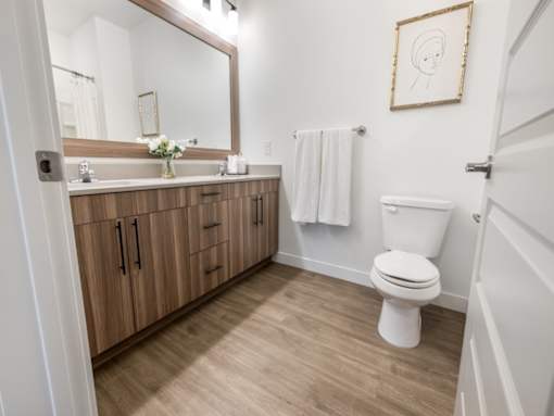 A bathroom with a toilet, sink, and mirror.