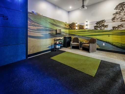 A room with a golf course mural on the wall and a green carpet.