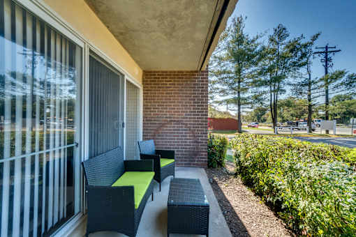 A patio with a bench and a table with a green cushion.