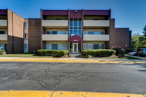 A multi-story apartment building with a red awning at the entrance.