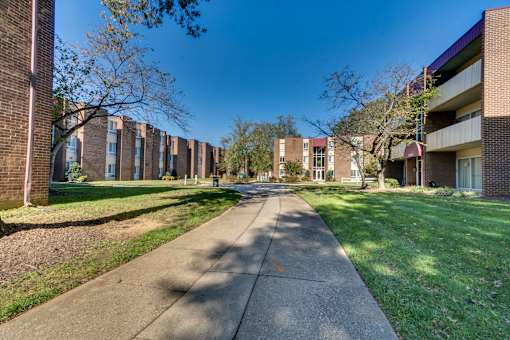 A long concrete walkway leads between apartment buildings.