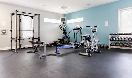 A home gym with a variety of equipment including a squat rack, treadmill, and weights.  Aviary Village Apartments, in Conway, SC 29526