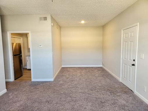 A room with a carpeted floor and a white door. The Cloisters Apartments, 902 67th Avenue North, Myrtle Beach, SC
