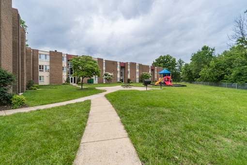 A playground with a blue roof is surrounded by apartment buildings.