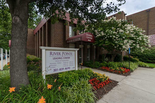 A leasing center named River Pointe is surrounded by greenery and flowers.