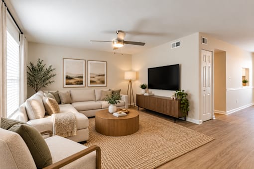 A living room with a white couch, a wooden coffee table, and a flat-screen TV.