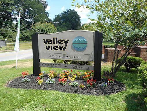 A sign for Valley View Apartments is surrounded by flowers and greenery.