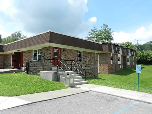 A small building with a red door and a handicap sign in front.