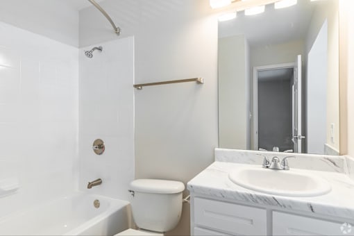 A white bathroom with a toilet, sink, and bathtub.