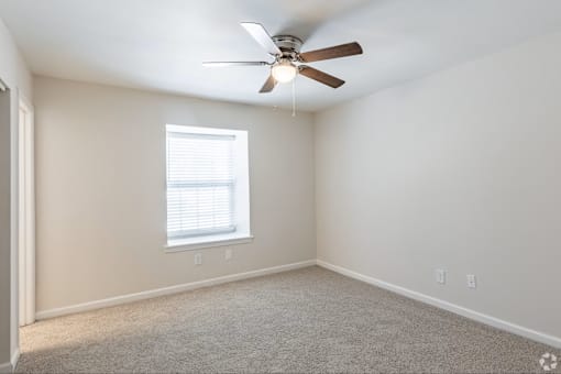 A room with a ceiling fan and a window.