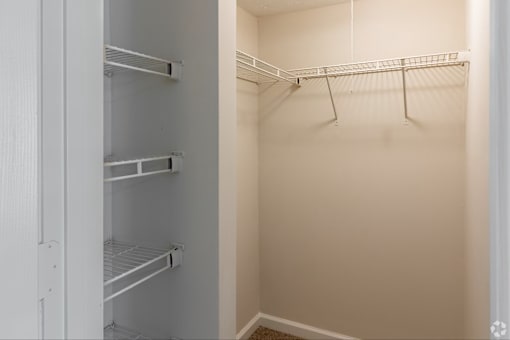 A white closet with a white door and shelves.