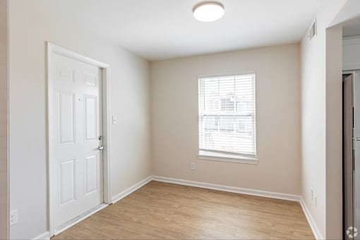 A room with a door, window, and wooden floor.