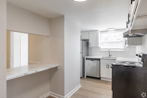 A kitchen with white cabinets and a black fridge.