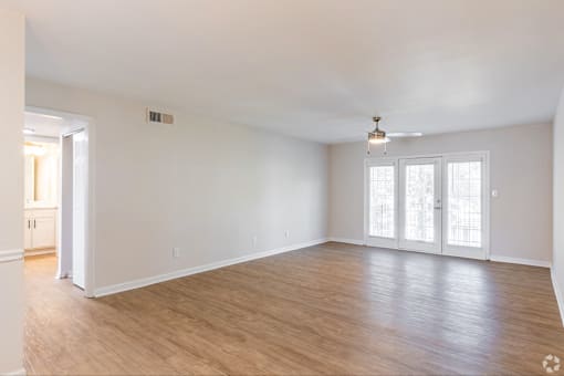 A spacious room with wooden flooring and a ceiling fan.