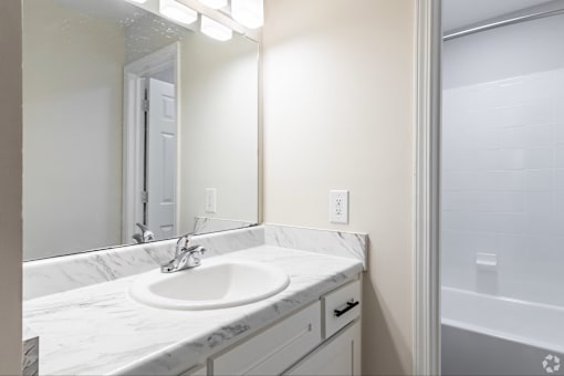 A white sink with a silver faucet is in a marble countertop.