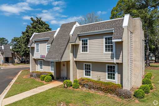 A two-story apartment building with a parking area in front.