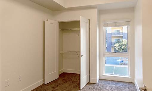 an empty bedroom with a closet and a window