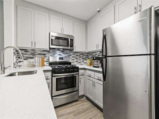 a kitchen with stainless steel appliances and white cabinets at Harbor Terrace Apartments, San Pedro