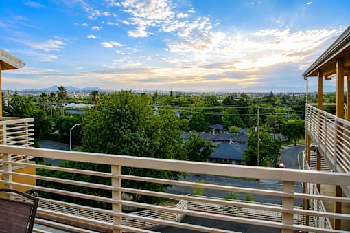 A balcony with a view of a town and trees.