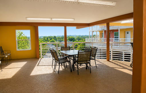 A dining table with chairs is in a room with yellow walls and a view of the outdoors.