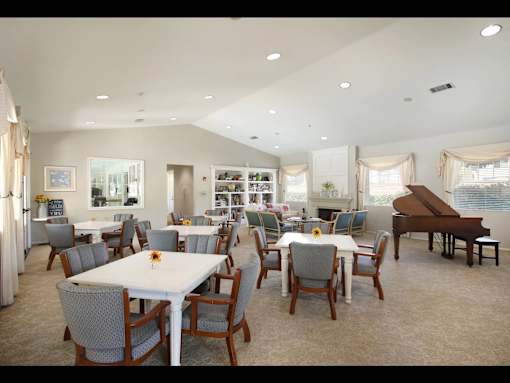 A room with a piano and a dining table with chairs.
