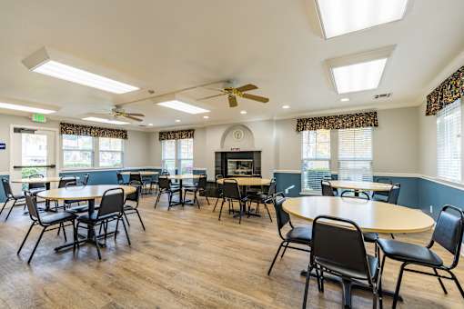 A room with tables and chairs and a ceiling fan.