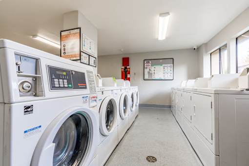 A row of white front load washing machines in a laundromat.