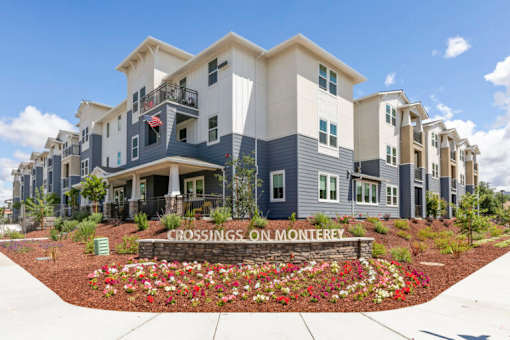 a crossroads on montgomery apartment building with a flower garden in front of it