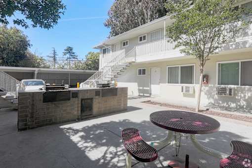 A patio with a table and chairs is in front of a white building.