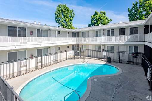 A swimming pool in a courtyard surrounded by a fence.