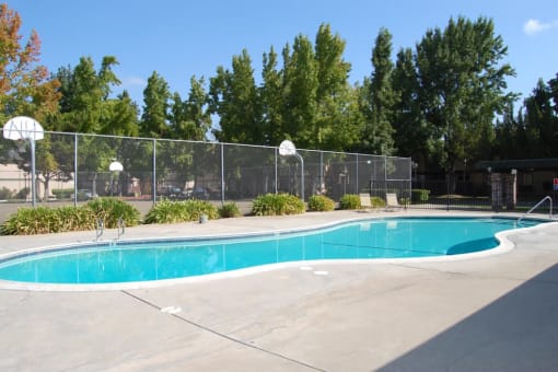 a swimming pool with a basketball court in the background