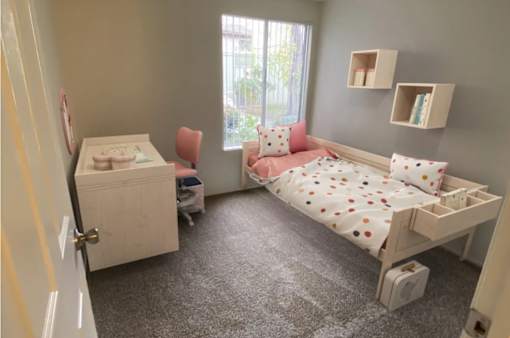 A baby's room with a crib and a bed with a pink pillow.