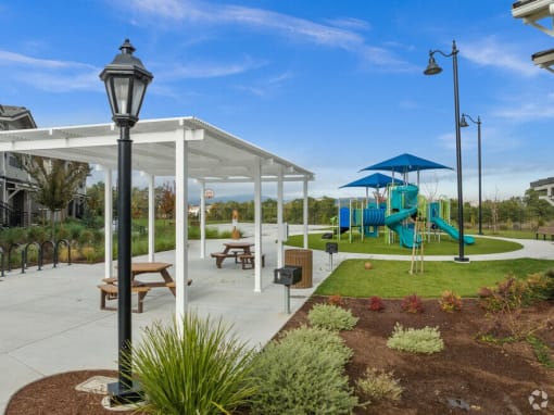 a playground and pavilion in a park with a blue slide