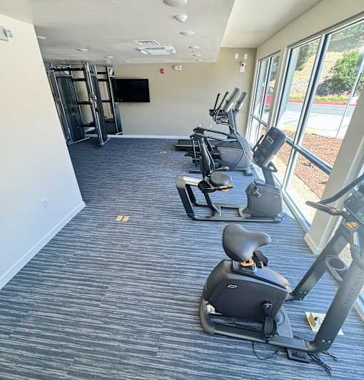 A gym with exercise equipment and a television.