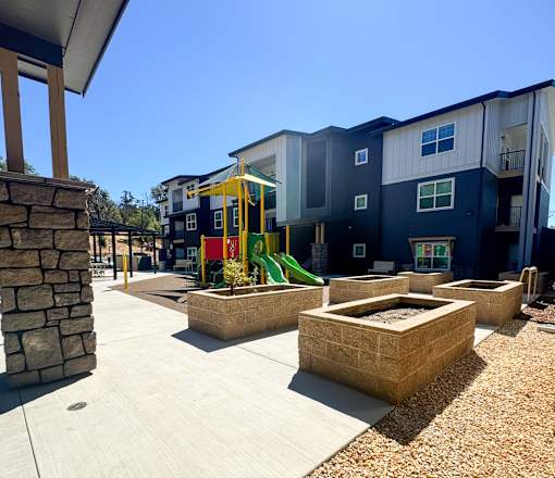A playground area with a slide and sandboxes in front of apartment buildings.