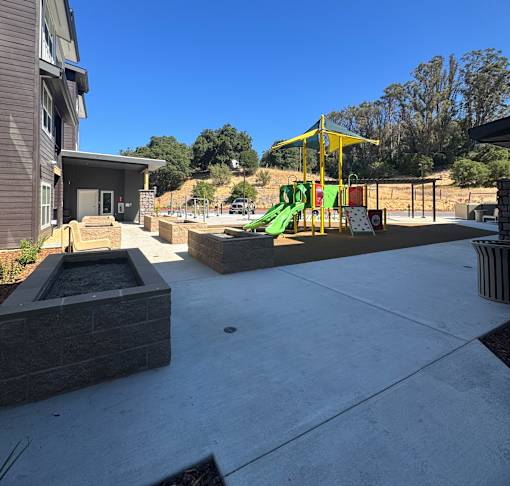 A playground with a yellow structure and a green slide.