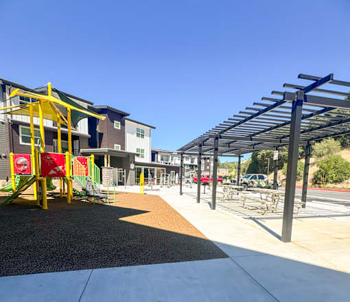 A playground with a slide and a building in the background.