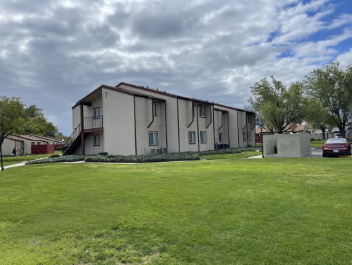 a white apartment building with a green yard and a cloudy sky